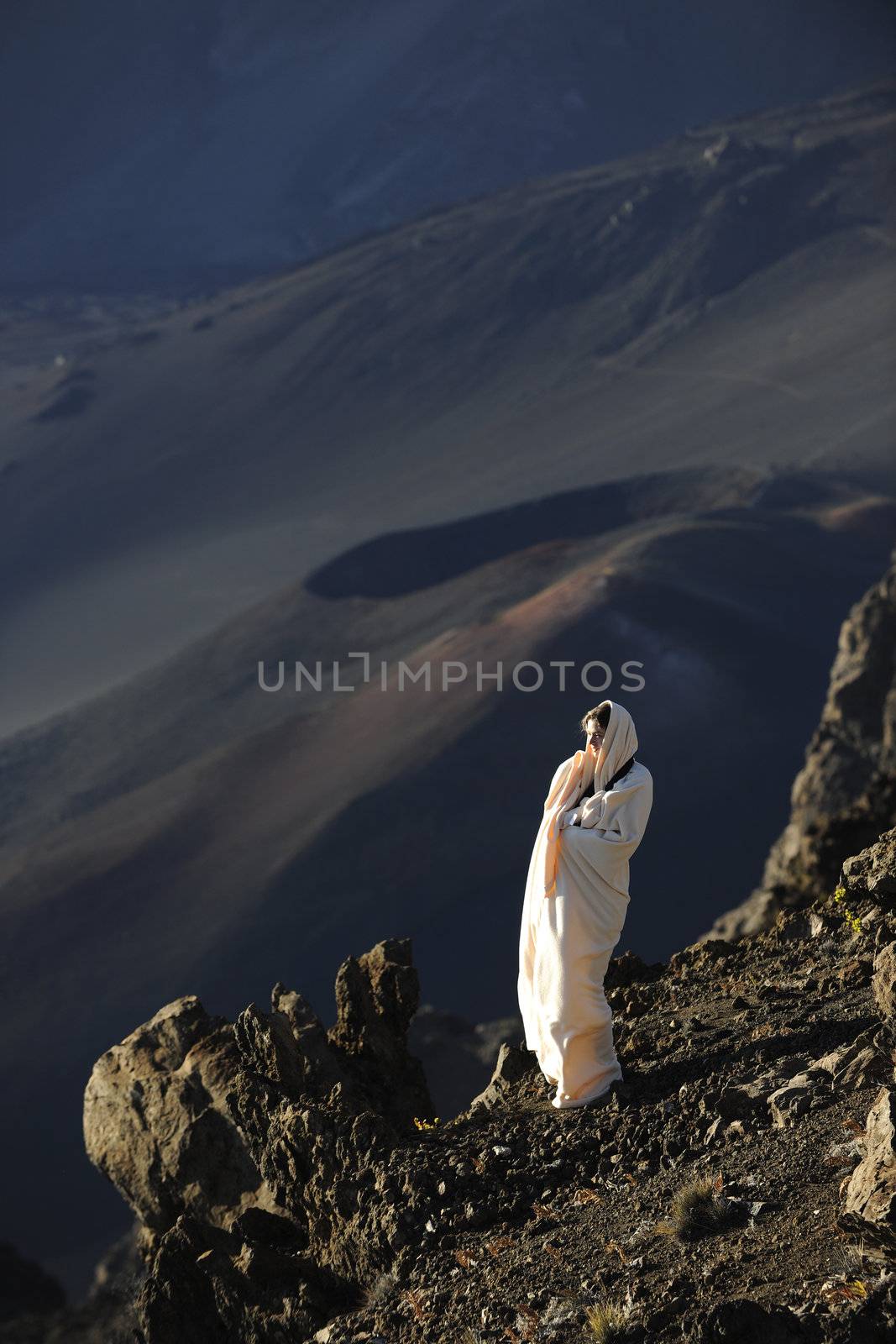 The girl at craters of Haleakala. Early morning, a smoke, wrapped up in white the girl in rising sun beams costs at edge of breakage against craters.