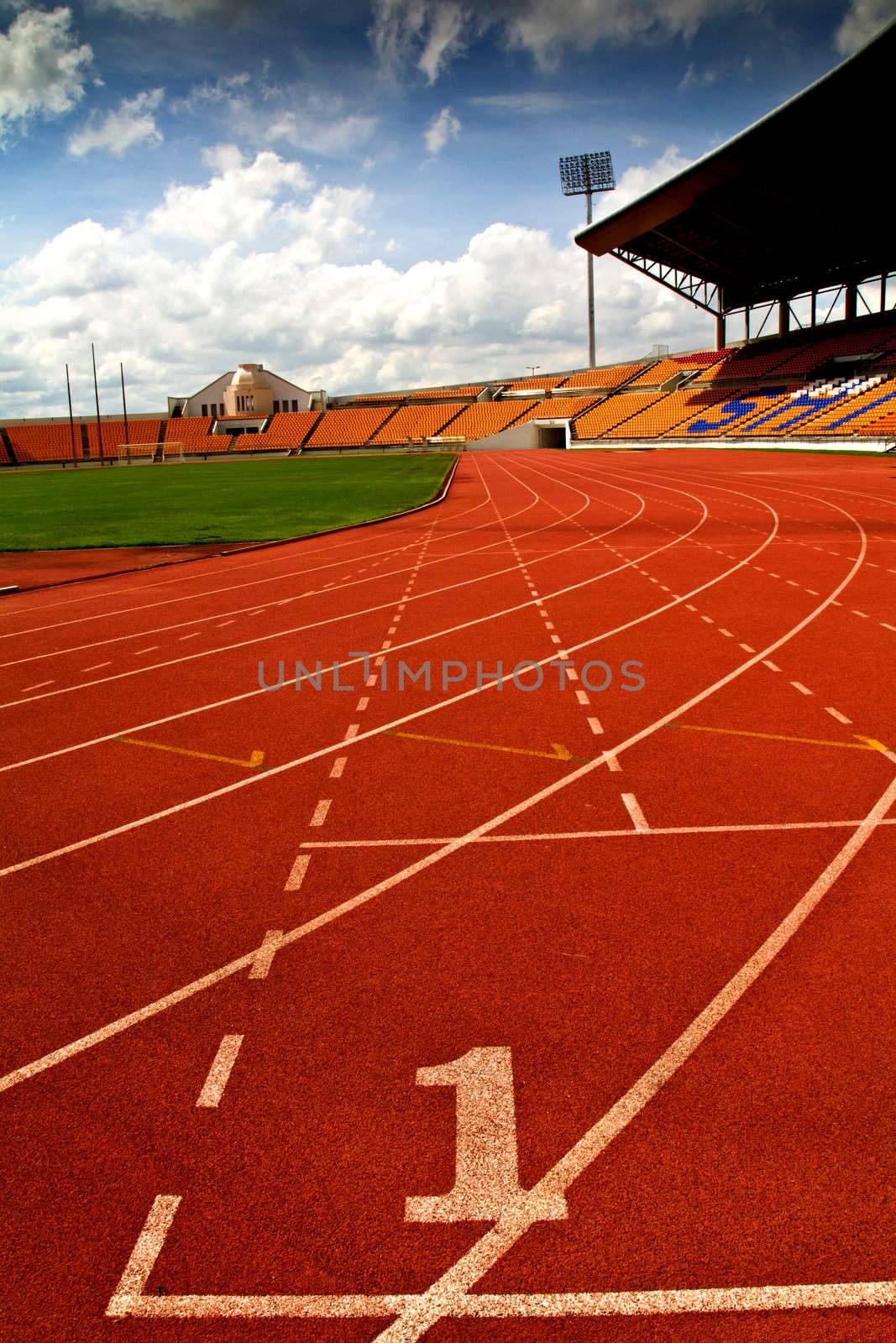 Running track number in front of tracks and stadium with blue sky and white cloud.