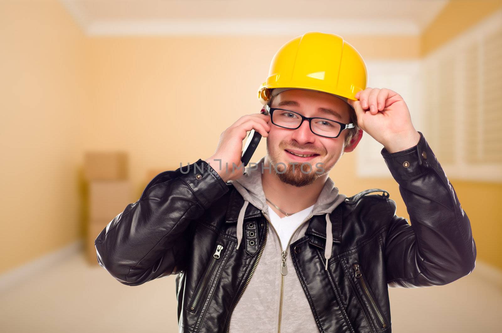 Young Contractor Wearing Hard Hat on Cell Phone Inside Empty House.