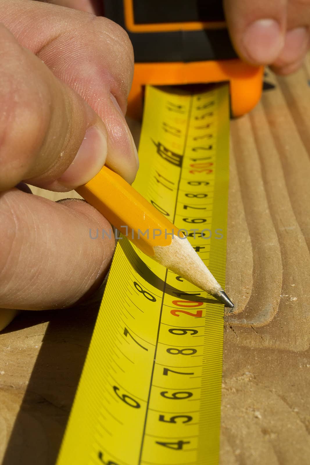 Closeup view of a worker measuring a piece of wood.