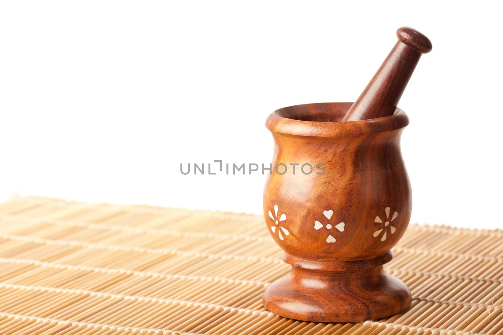 Wooden mortar with pestle on bamboo mat