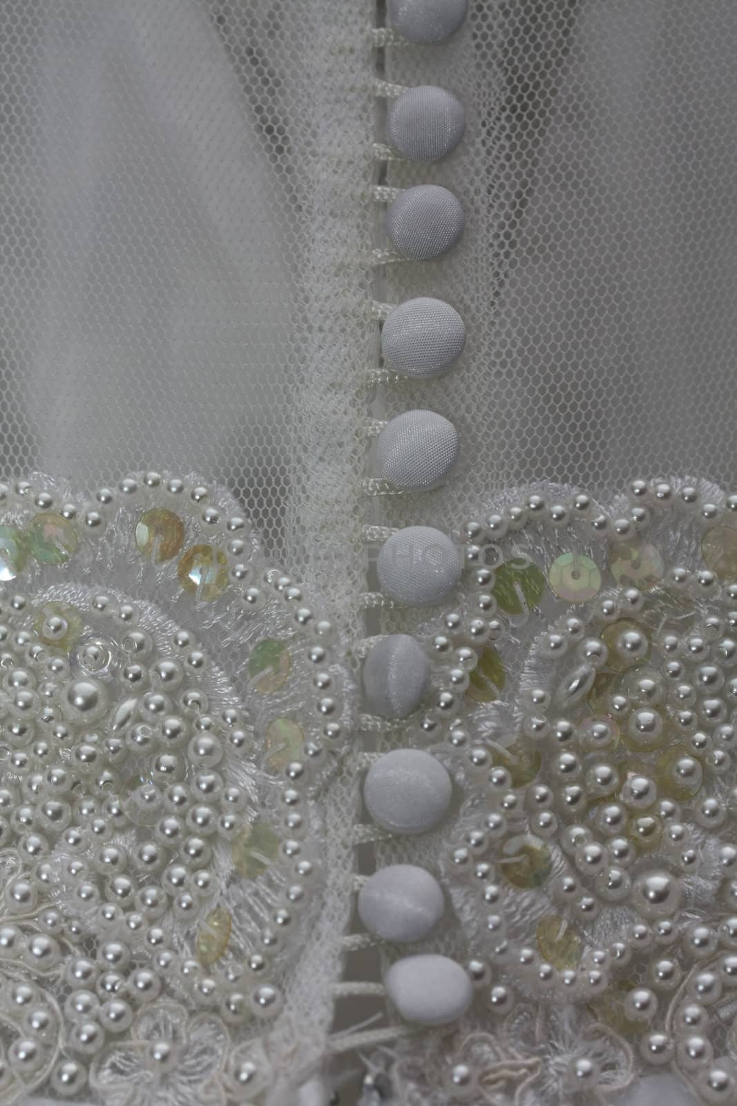 Detail of a white bridal gown or wedding dress with pearls and white buttons