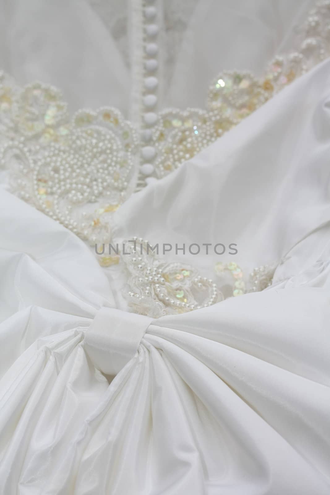 Detail of a white bridal gown or wedding dress with pearls and white buttons