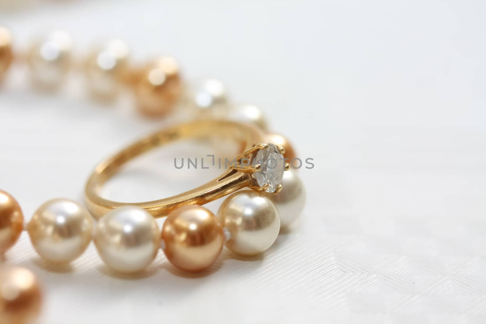 A solitaire diamond engagment ring on a pearl necklace