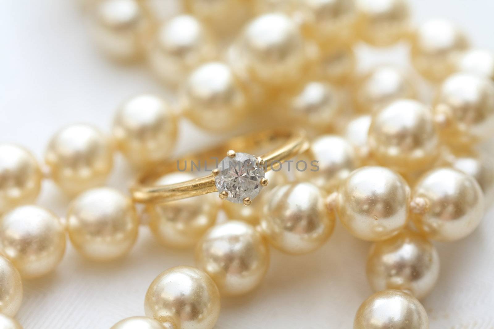 A solitaire diamond engagment ring on a pearl necklace