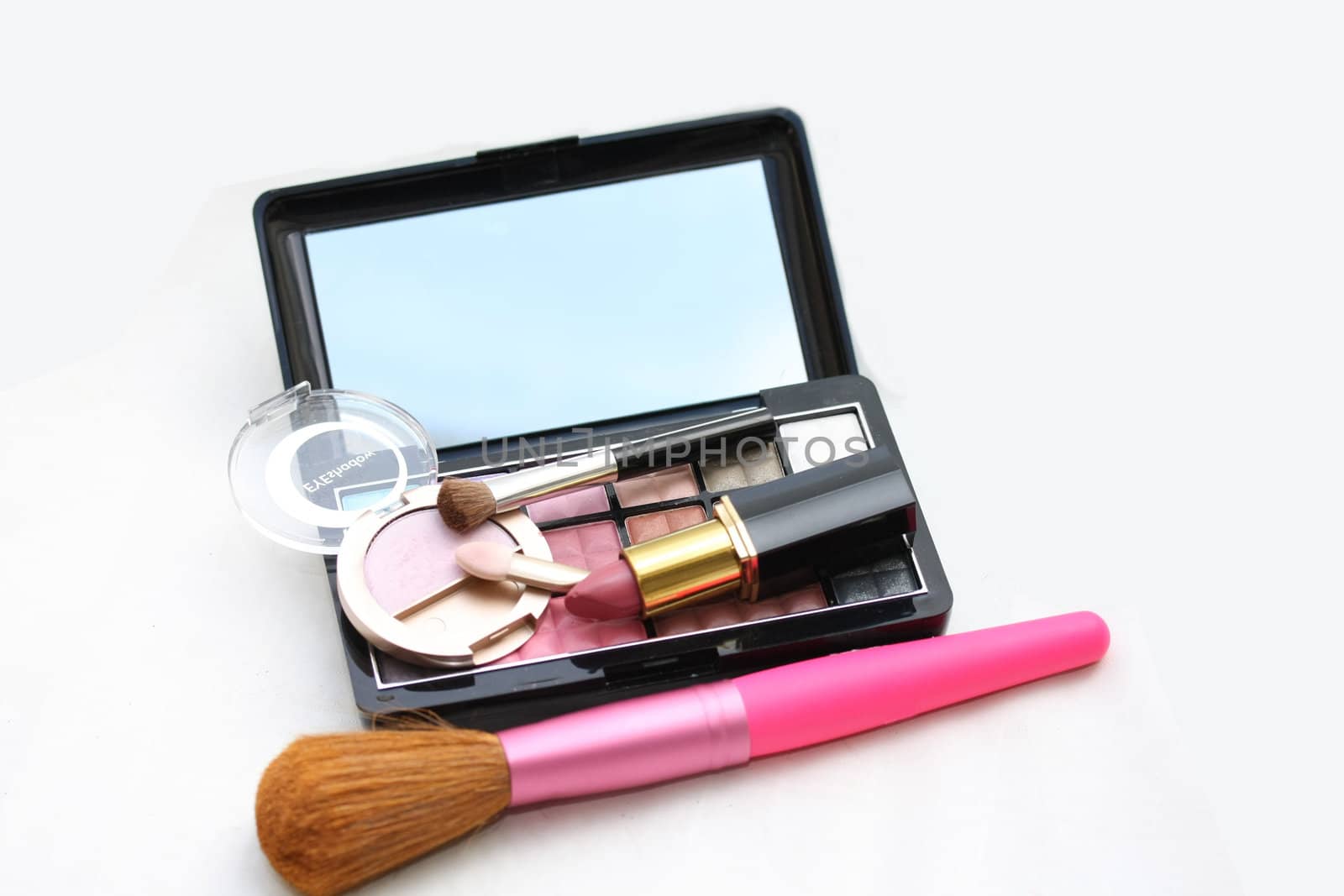 A palet with different shades of eye shadow, pink lipstick and a brush