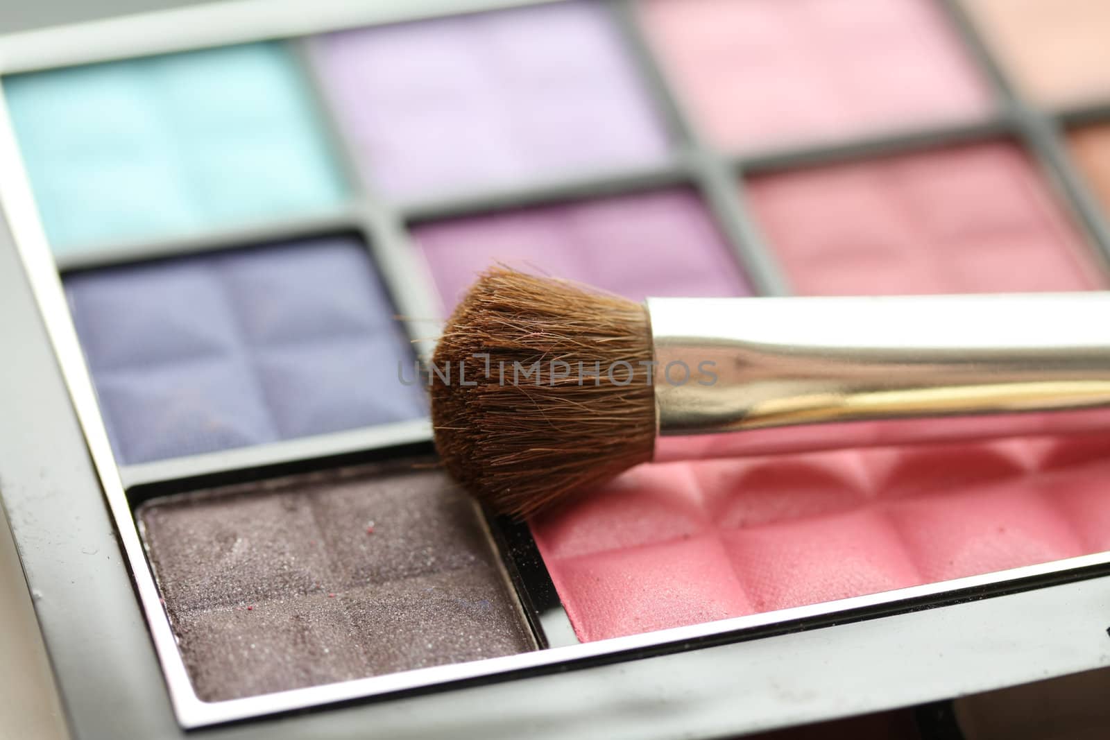 A palet with different shades of eye shadow and a brush