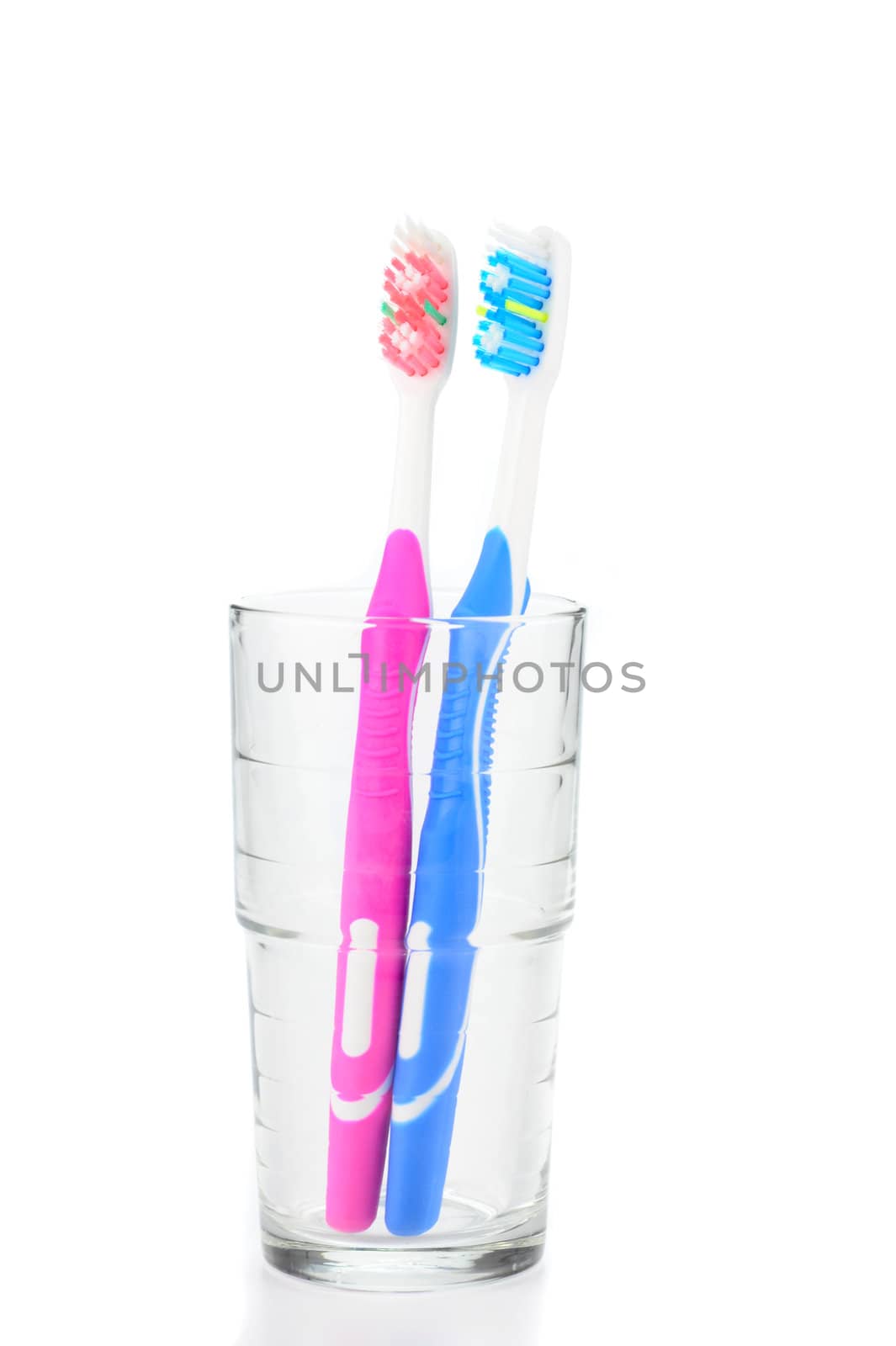 Pink and blue toothbrushes in a water glass.