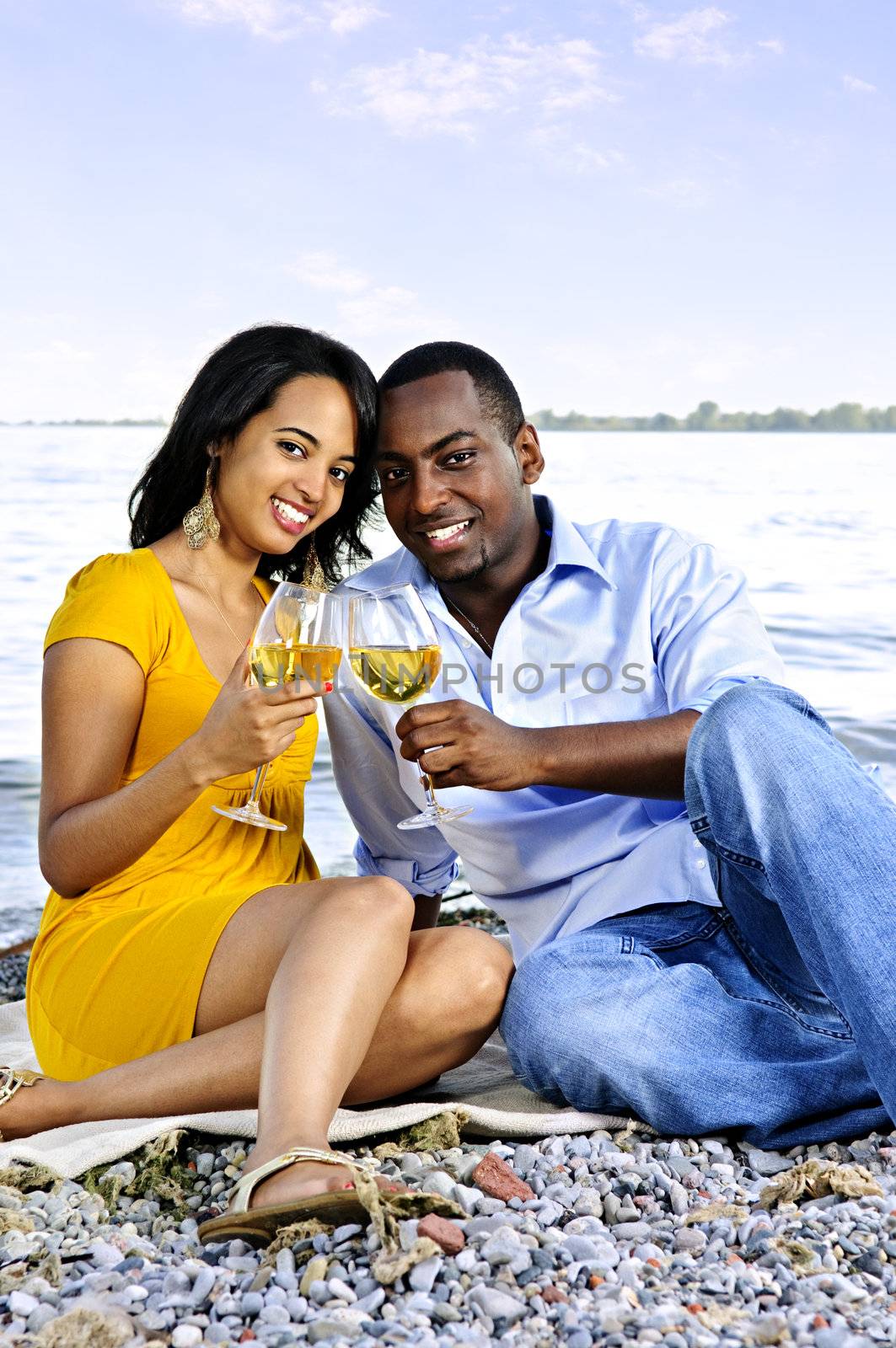 Young romantic couple celebrating with wine at the beach
