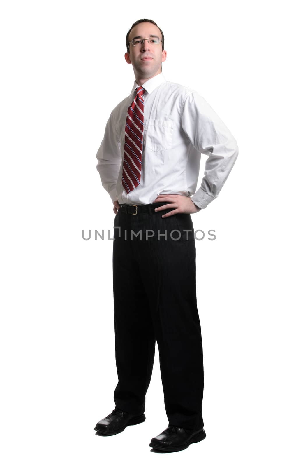 A full length view of a successful businessman standing with his hands on his hips, isolated against a white background.