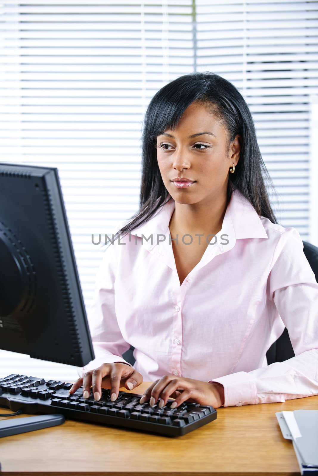 Serious black businesswoman at desk by elenathewise