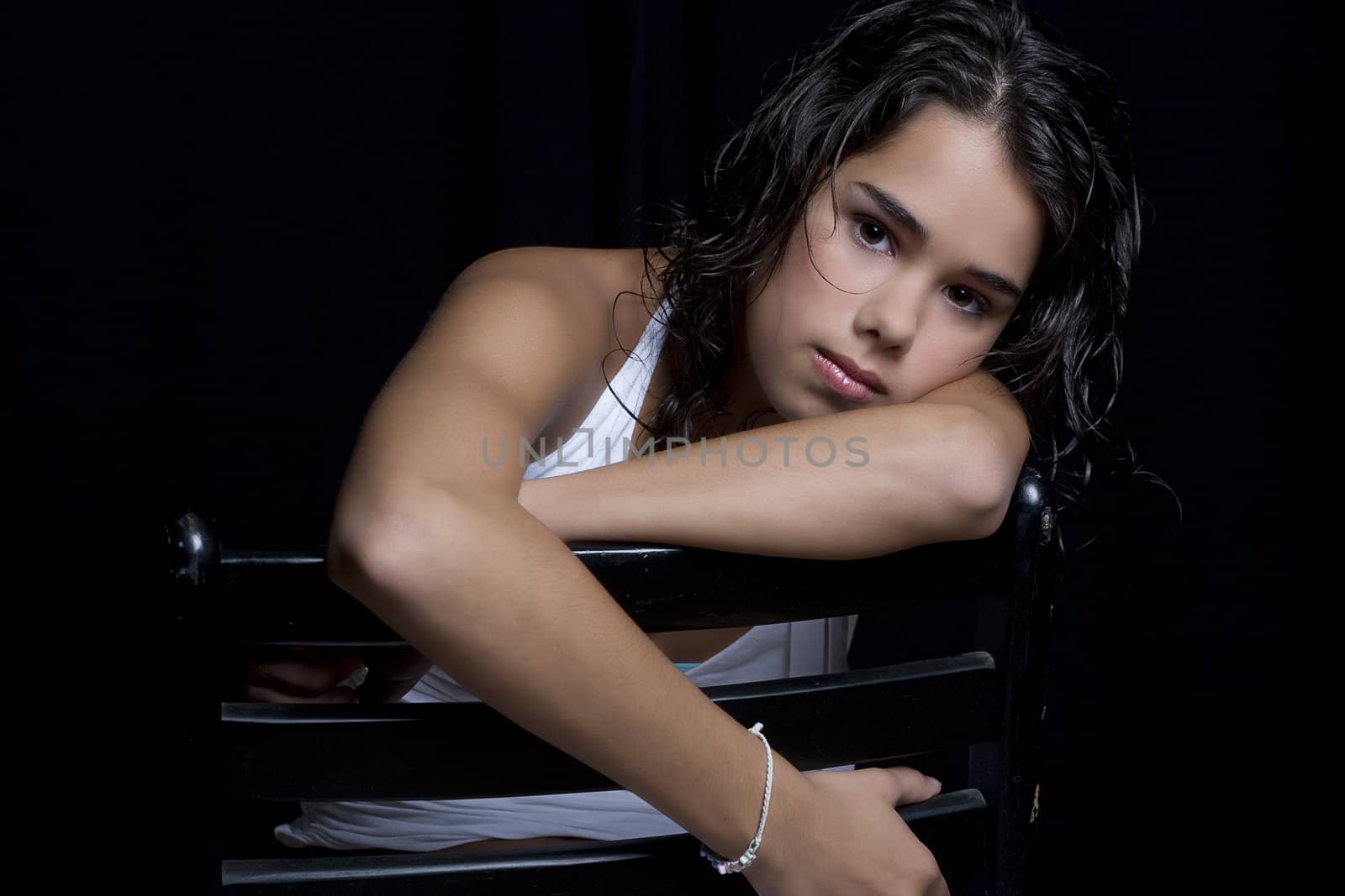 young woman relaxing on a chair against a black background