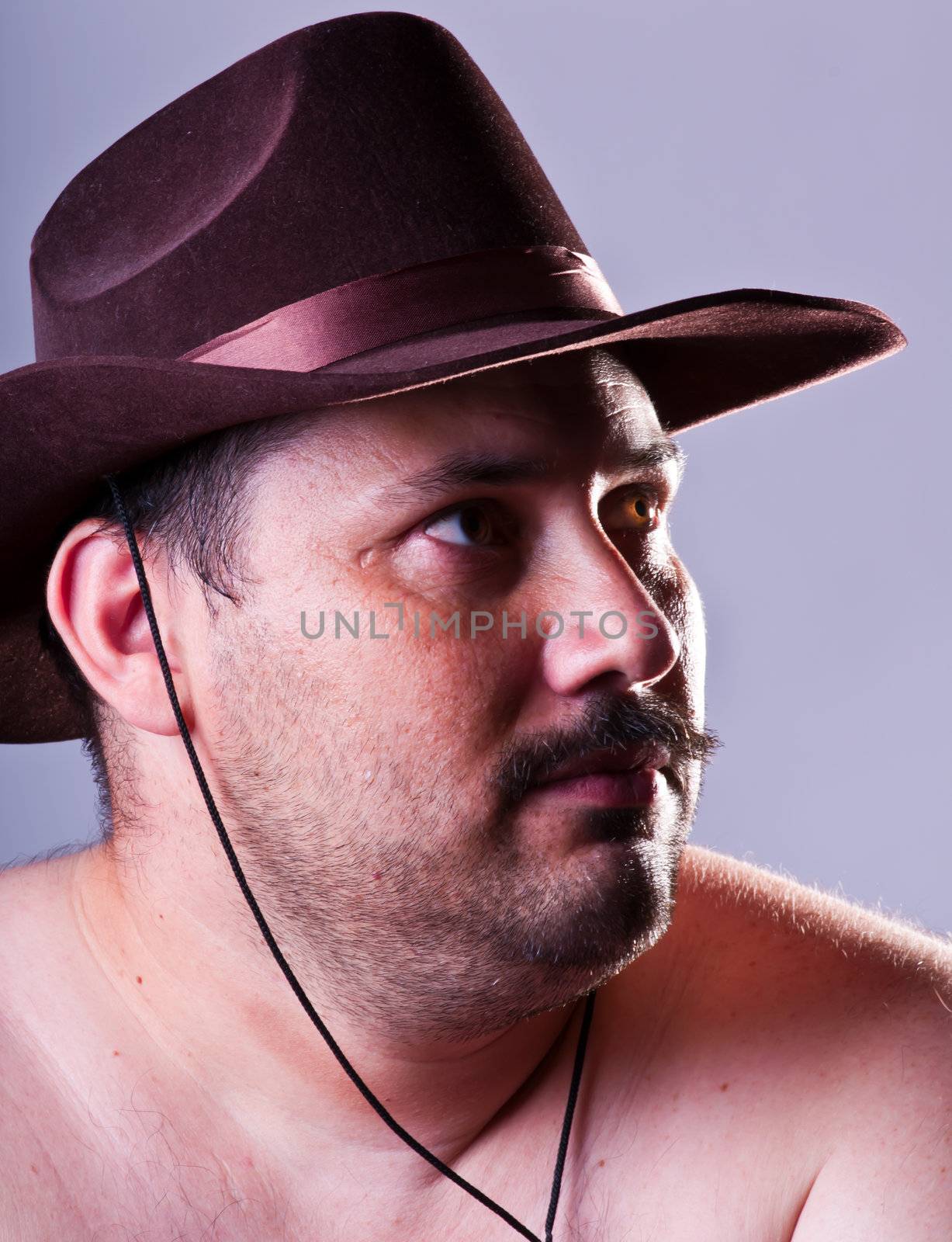 Portrait of the unshaven man in a hat in studio