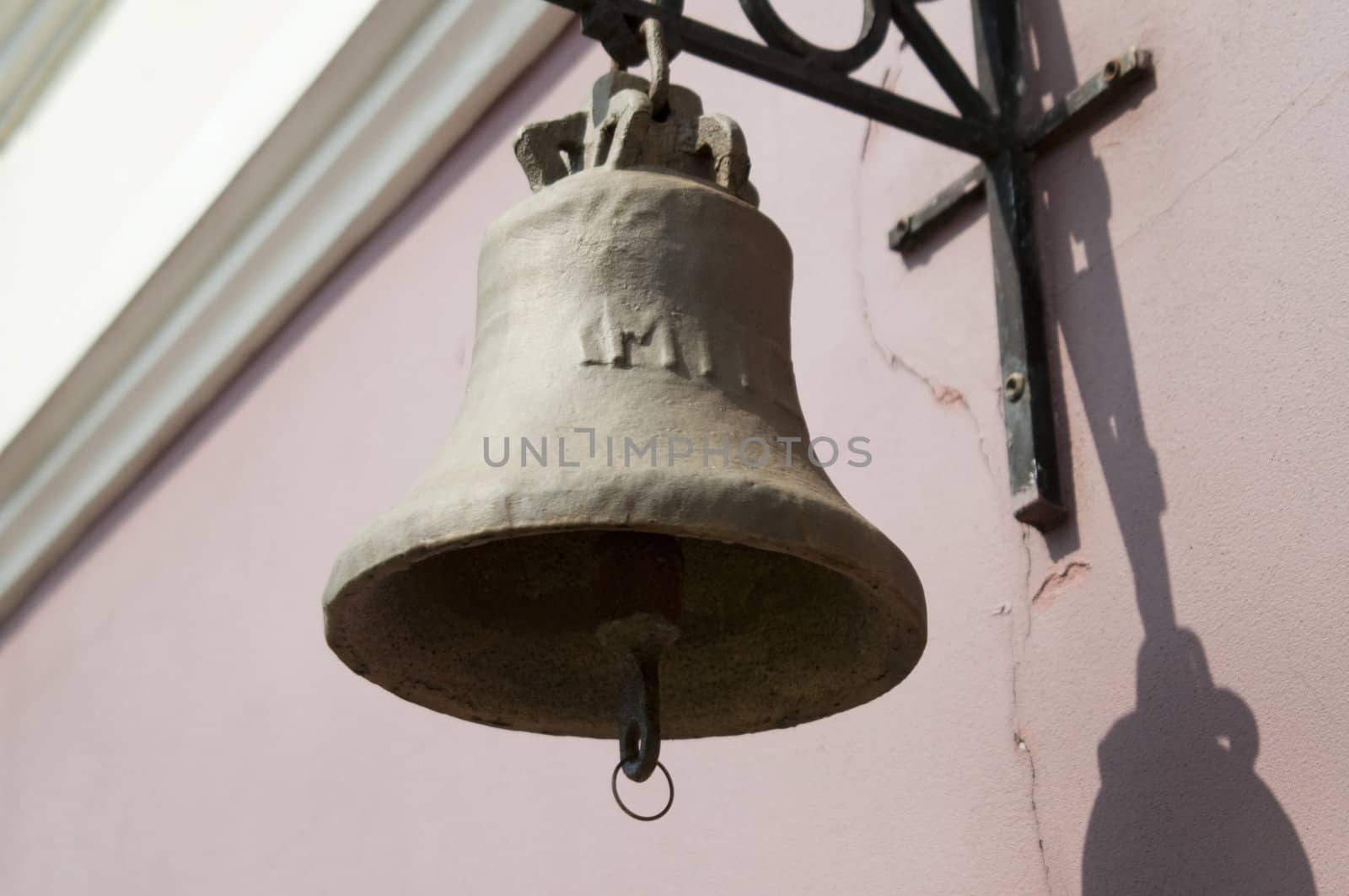 High resolution image. The ancient, bronze bell hangs on a wall.