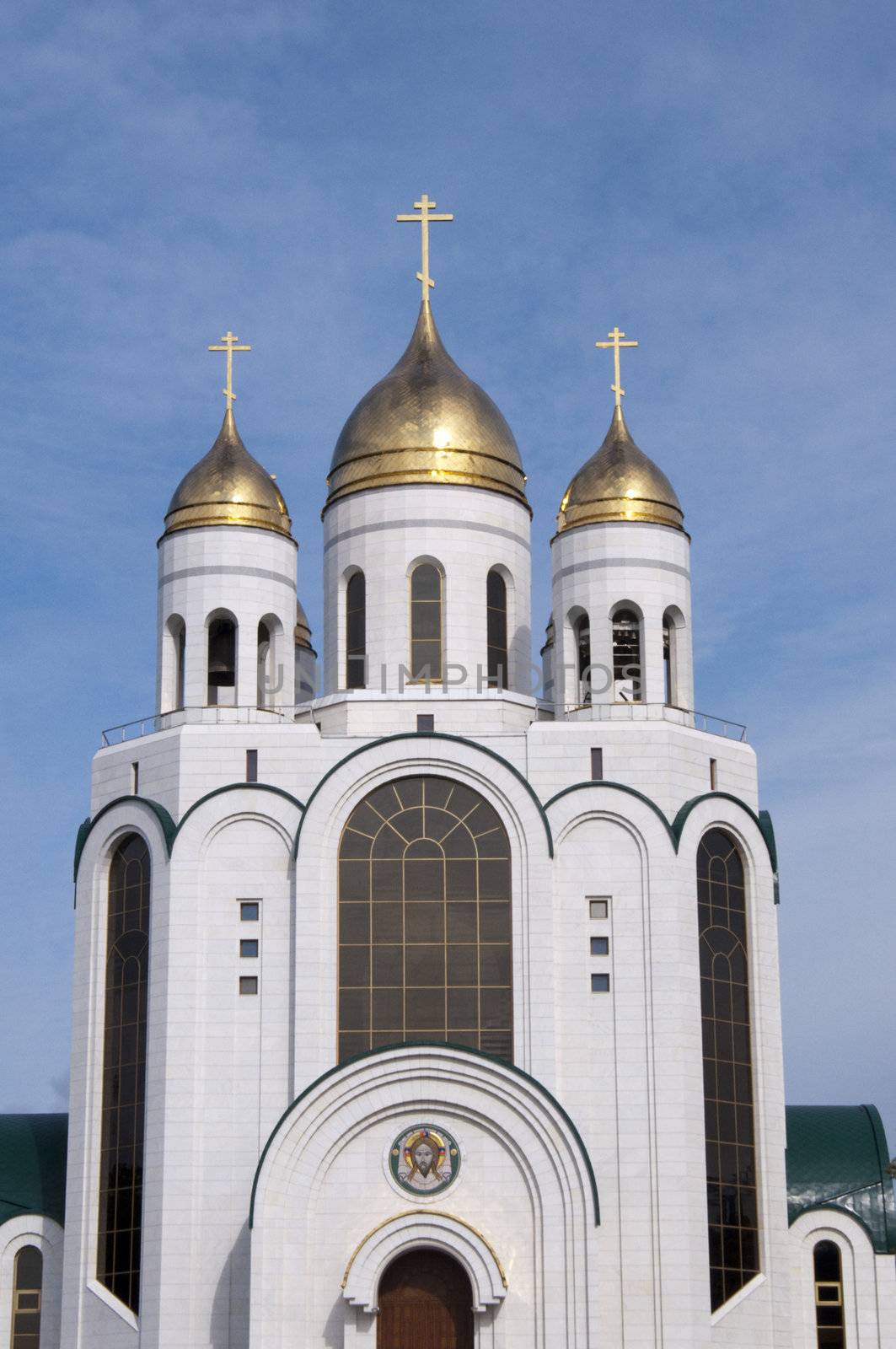 High resolution image. Russian cathedral with gold cupola, bell-tower and icons over entrances.