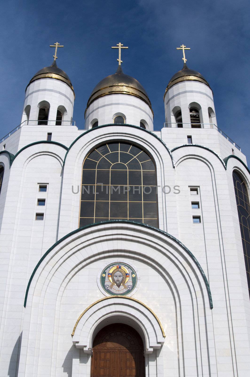 High resolution image. Russian cathedral with gold cupola, bell-tower and icons over entrances.