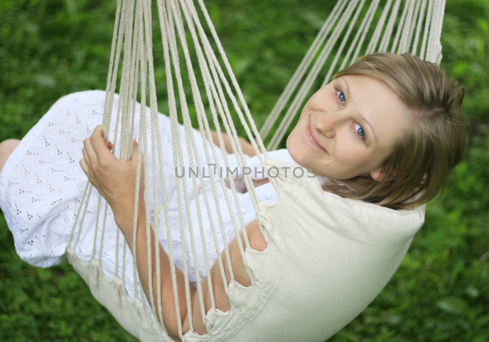 Young happy woman relaxing and swinging in hammock. Soft focus.