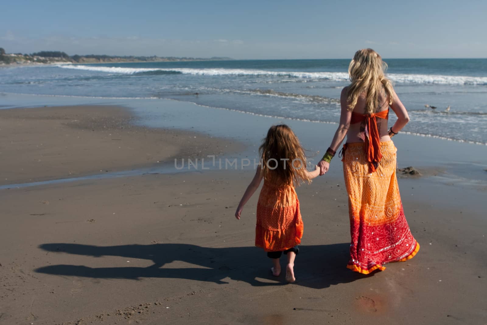 Mother and daughter walking on beach by drsPIX