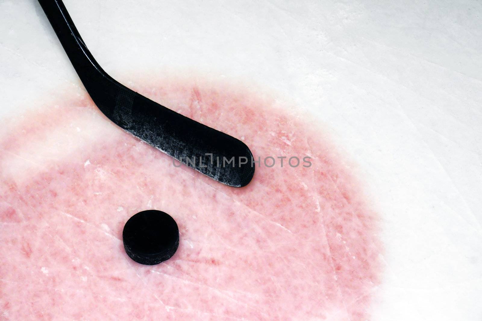 Hockey sport background: graphite stick and puck on real arena used and scratched ice.