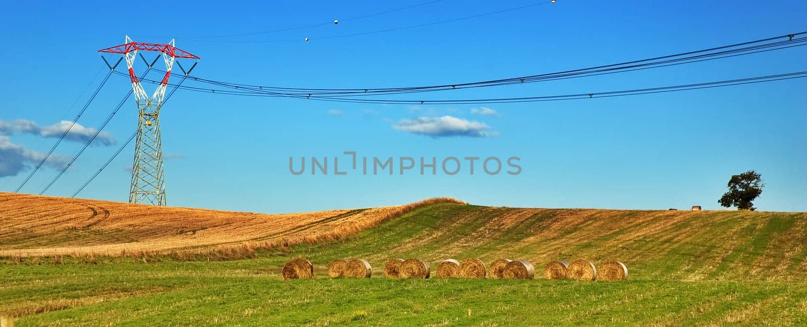 Italian landscape with power pylon and hay bales