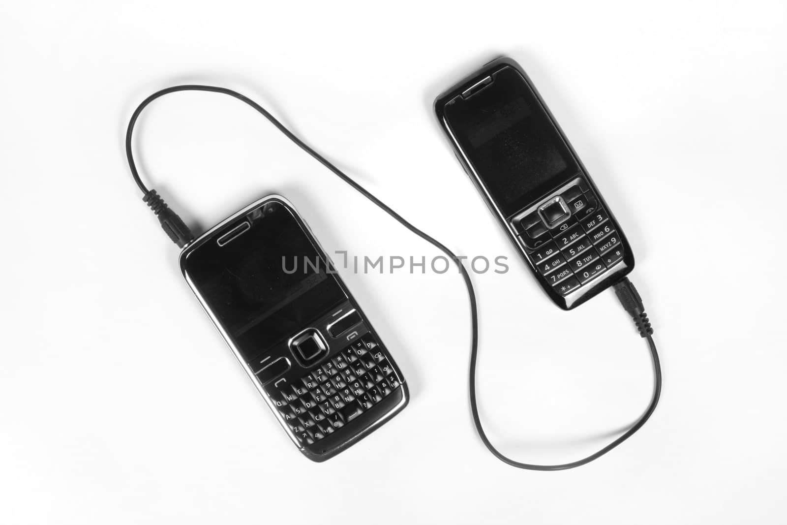 A smartphone and a normal phone connected with a cable, on white background.