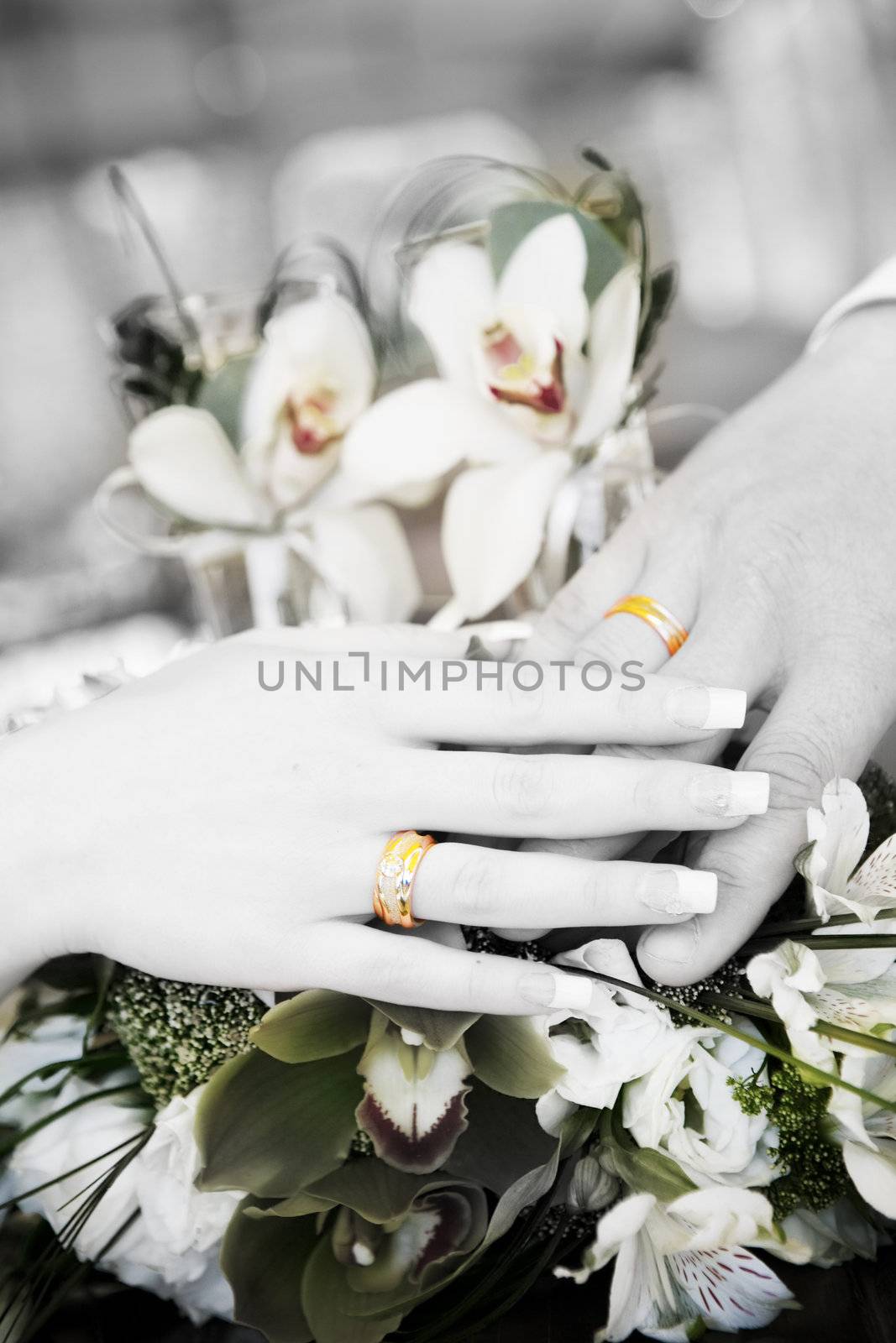 hand of groom and hand of bride with wedding rings on the flower bouquet in black and white