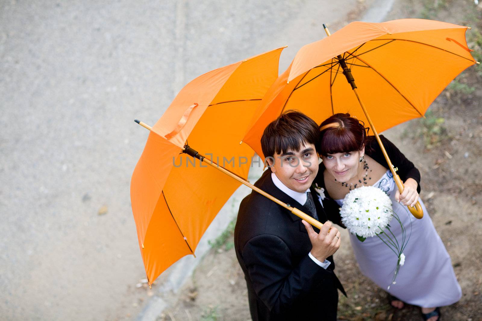 happy bride and groom with orange umbrellas 