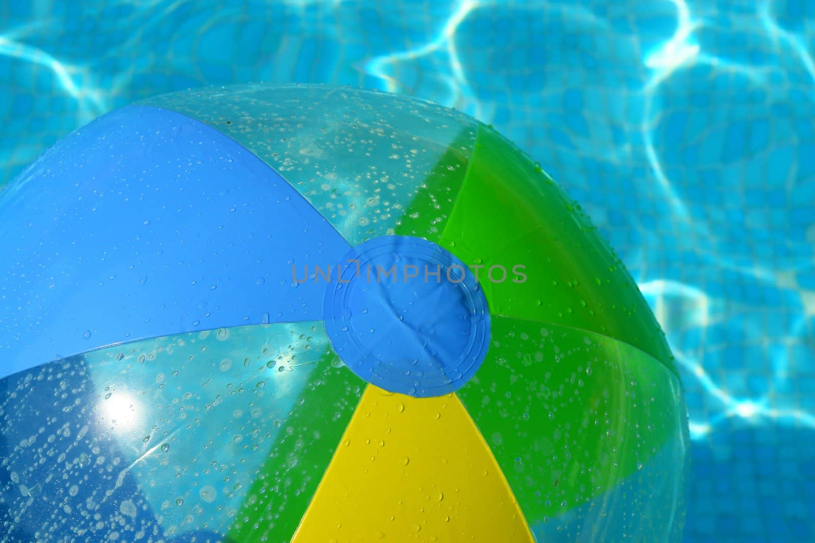 A colorful beach ball floating on the swimming pool.