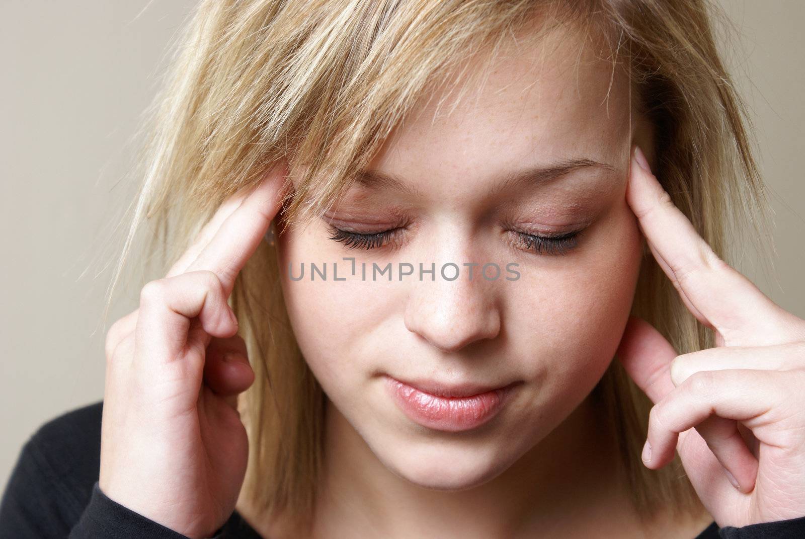 A young woman relieves the pain from her headache by putting pressure on her temples.