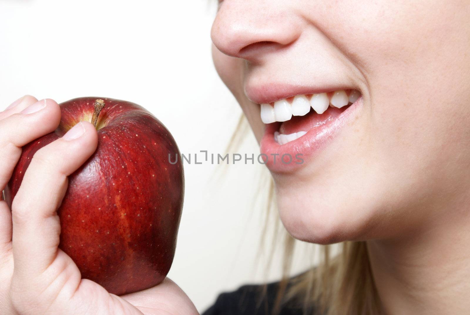 A happy young woman stays healthy by eating some ripe fruit.