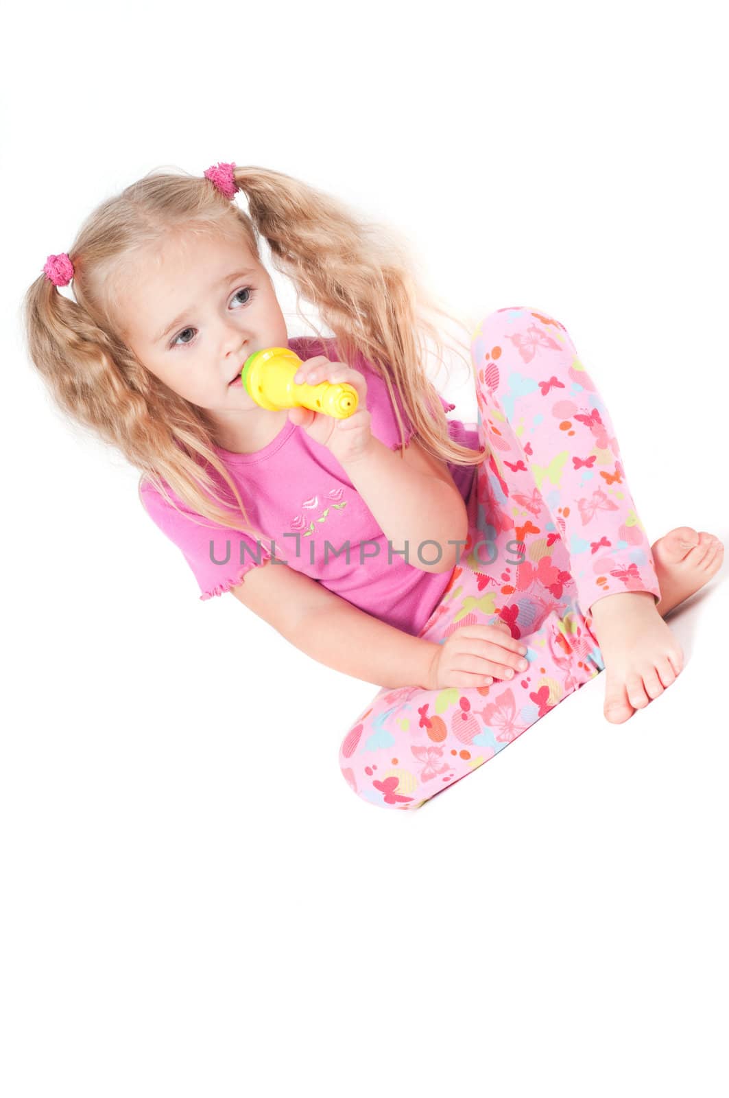 Little cute girl in pink and with ponytails in studio