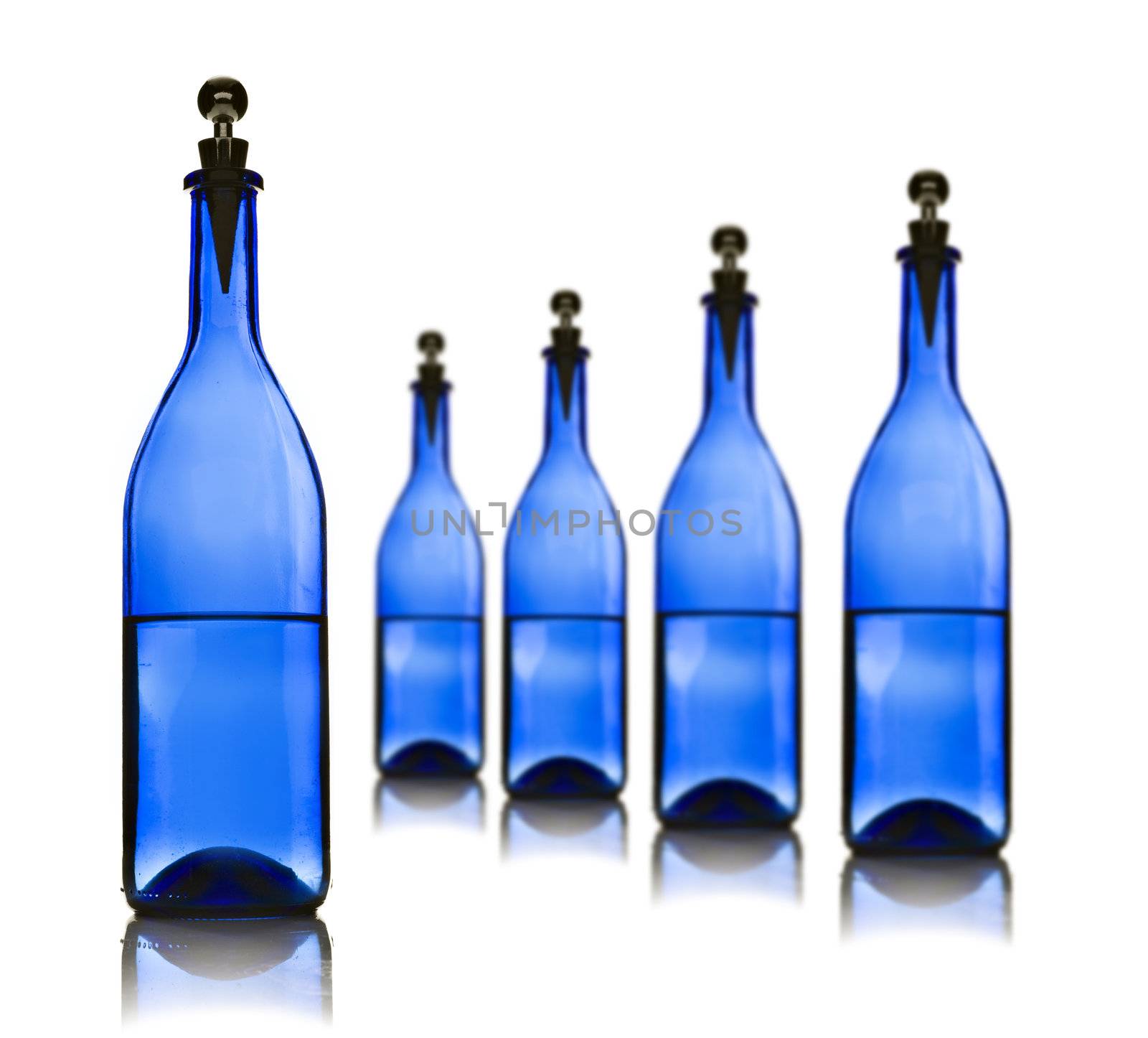 Five blue glass bottles with water on a white by tish1