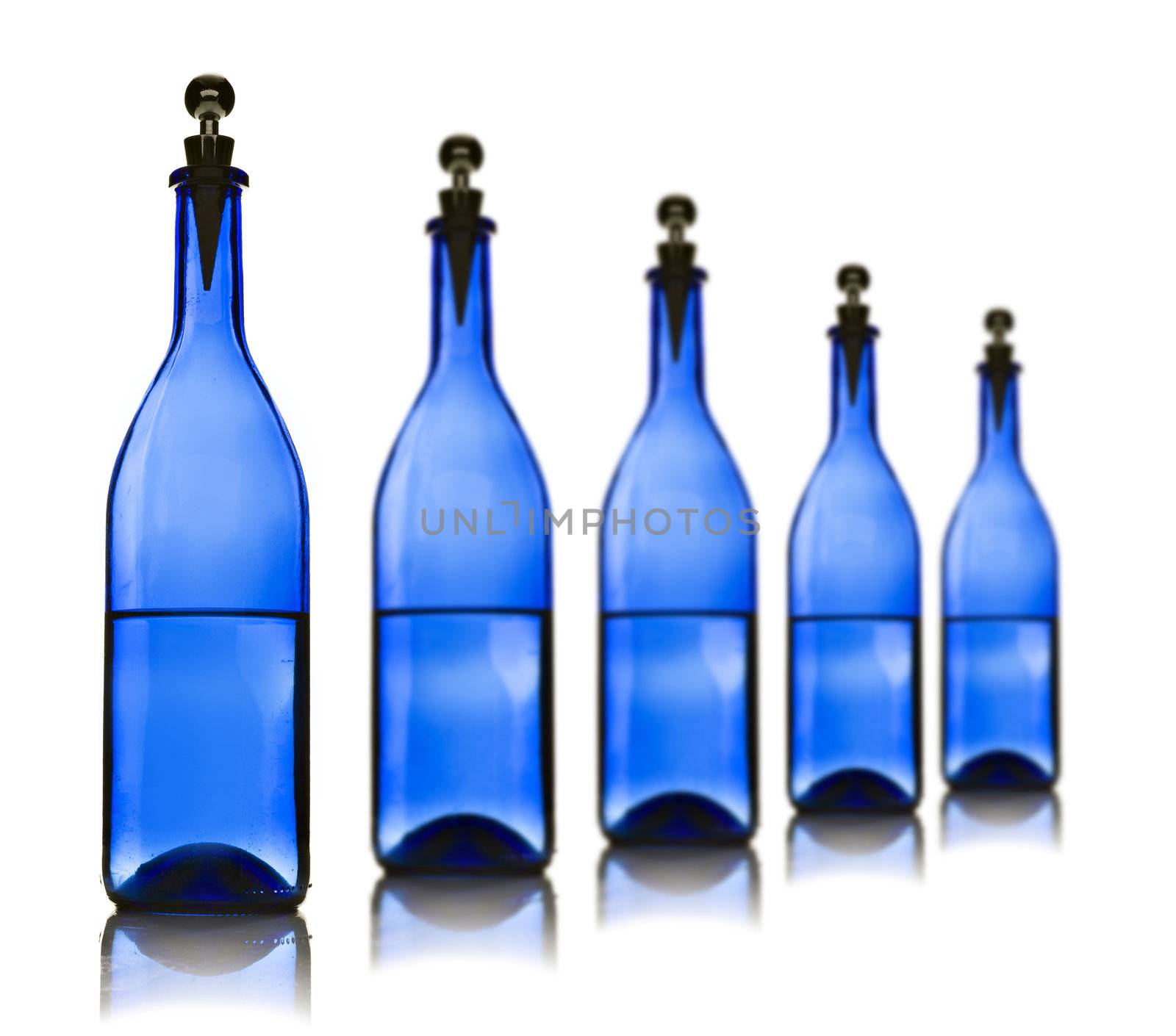Five blue glass bottles with water on a white background