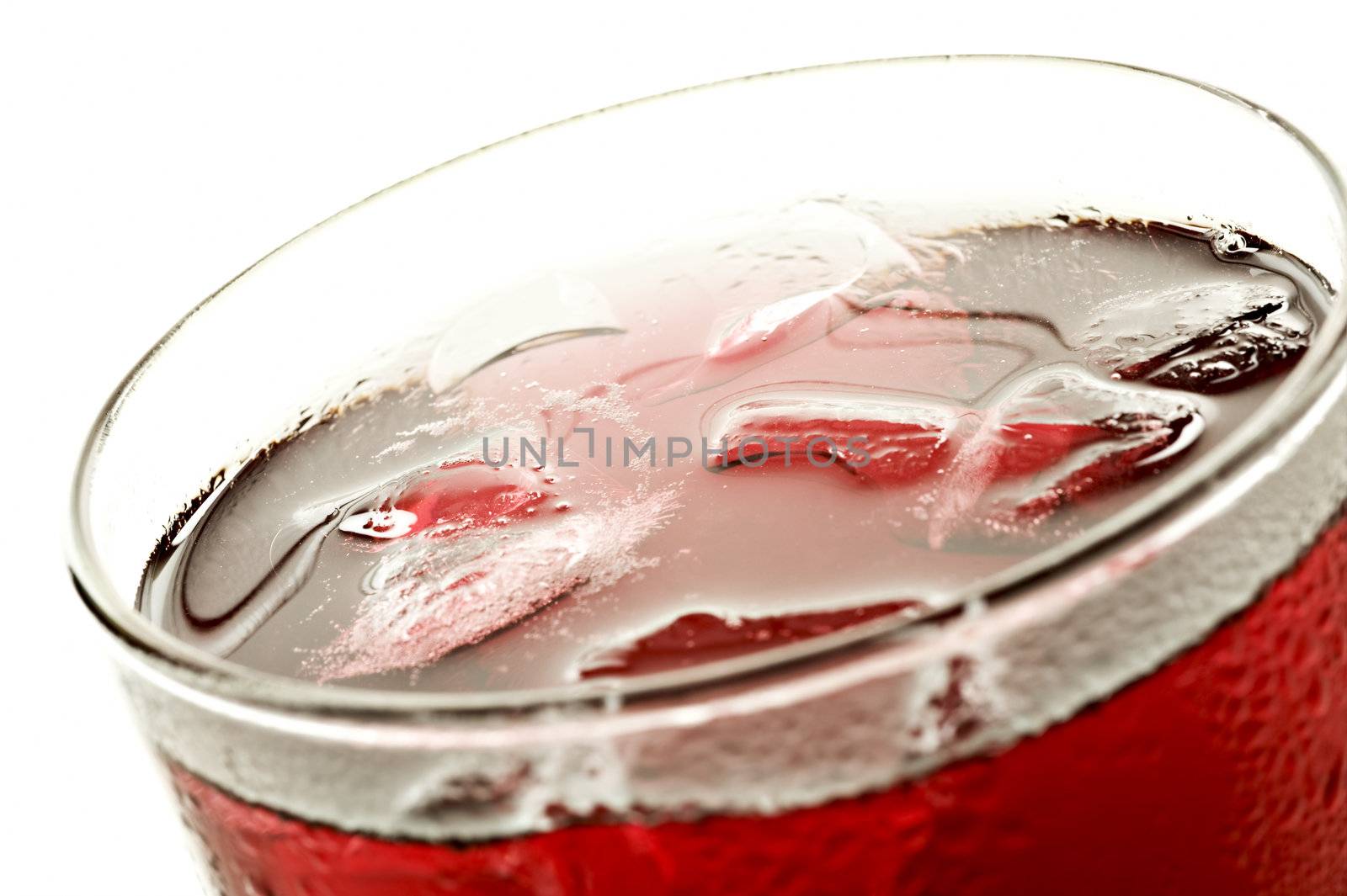 Close up of  a glass of red fruit juice on a white bakcground