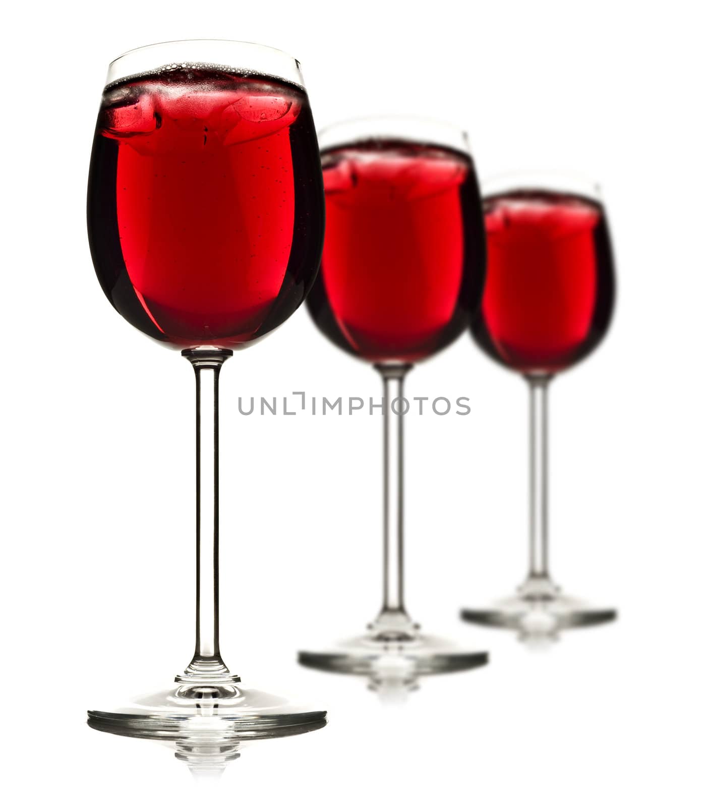Three wine glasses with red fruit juice and ice with shallow depth of field