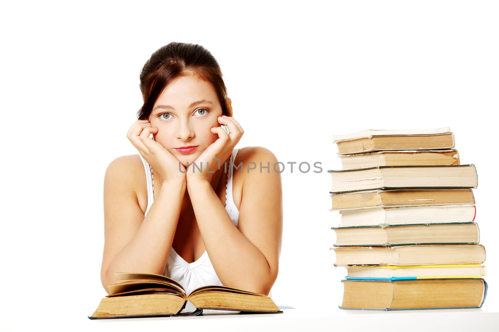 Young girl holding her head and sitting with books. by BDS