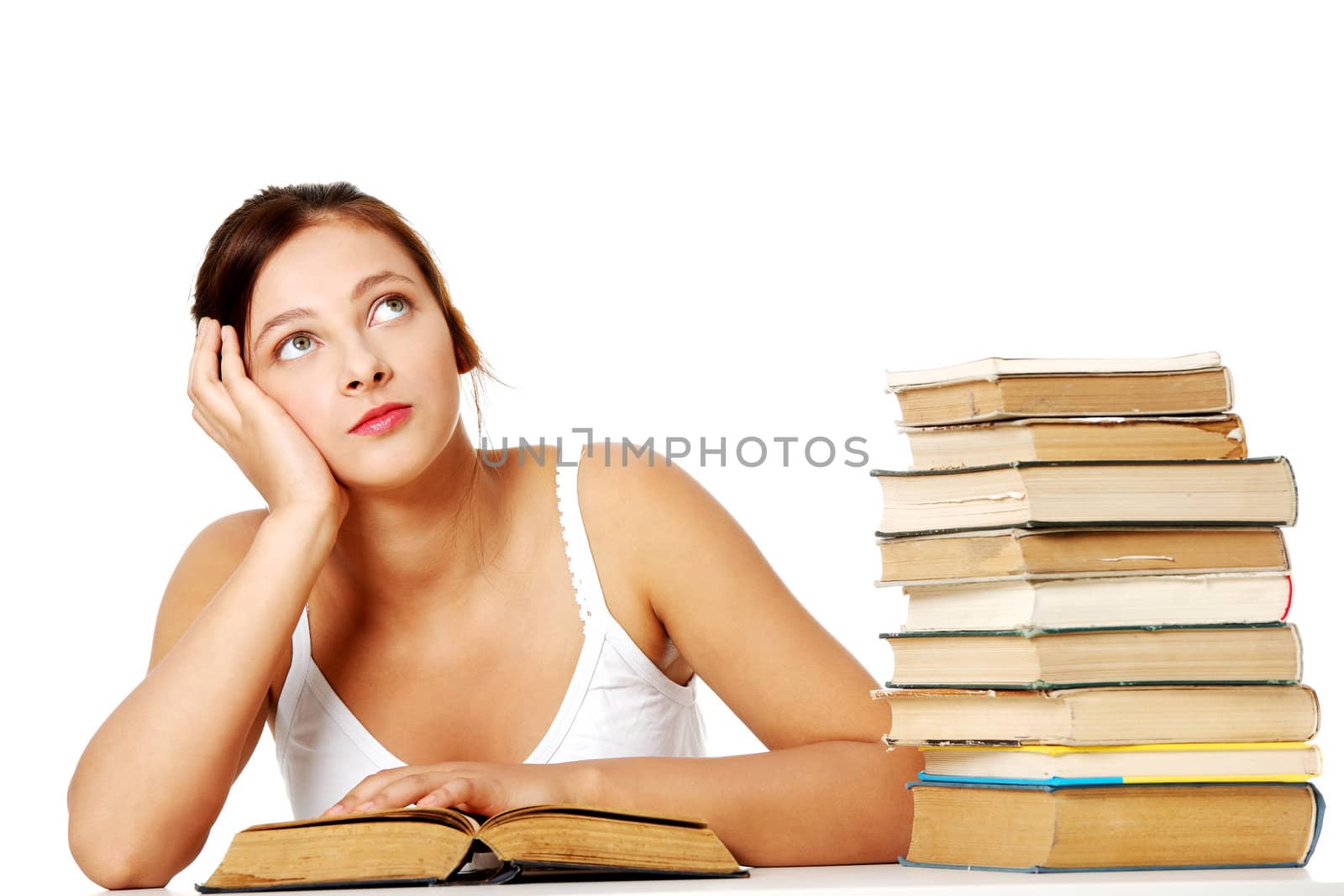 Young girl sitting with book near the pile of books and thinking. Isoalted on white.