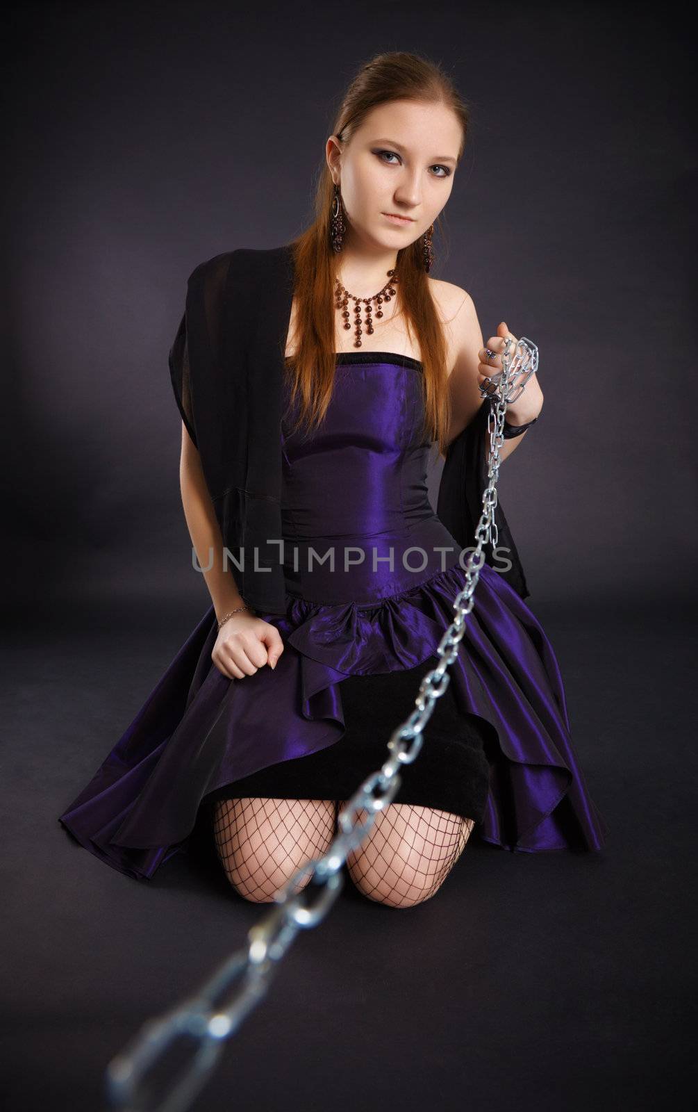 Young beautiful girl pulls out a chain leash on black background