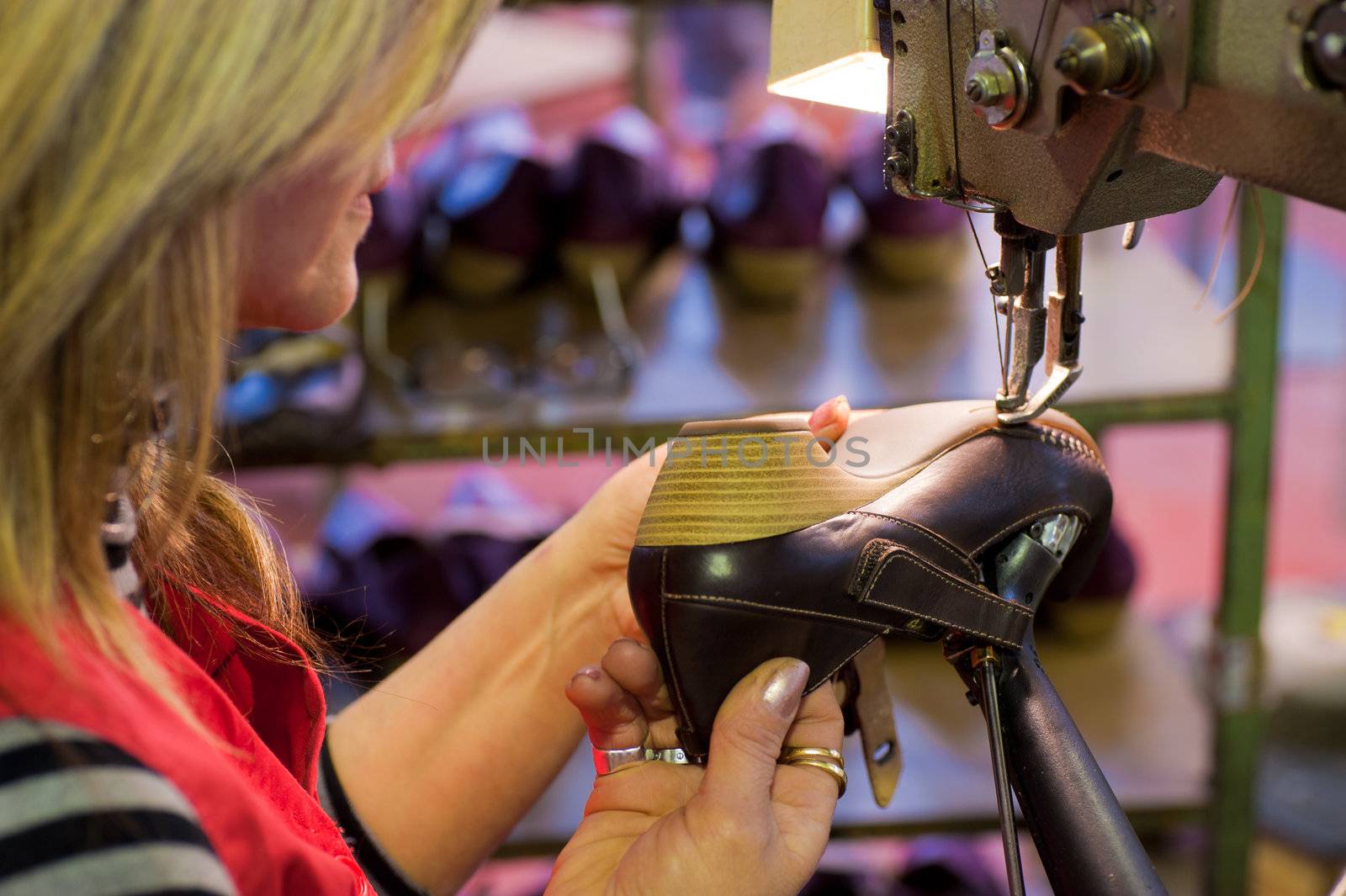 Experienced worker sewing leather shoes in a production line