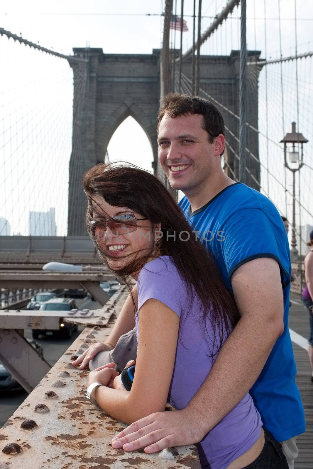 A smiling couple of tourists visit Brooklyn New York by the world famous Brooklyn Bridge.