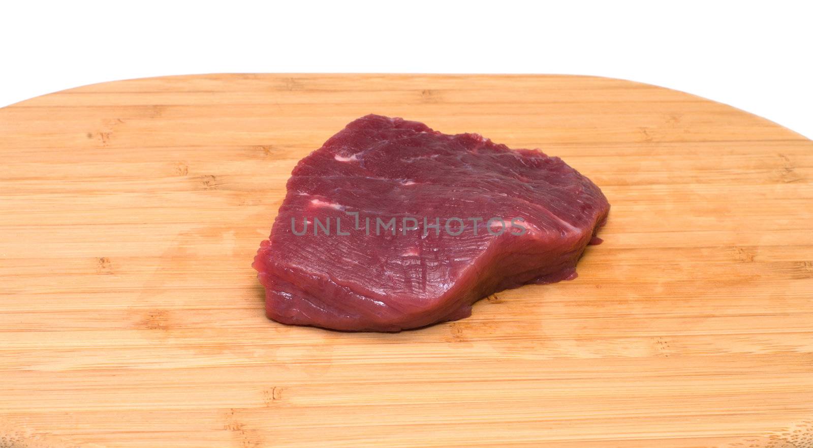 Piece of beef on a wooden cutting board.