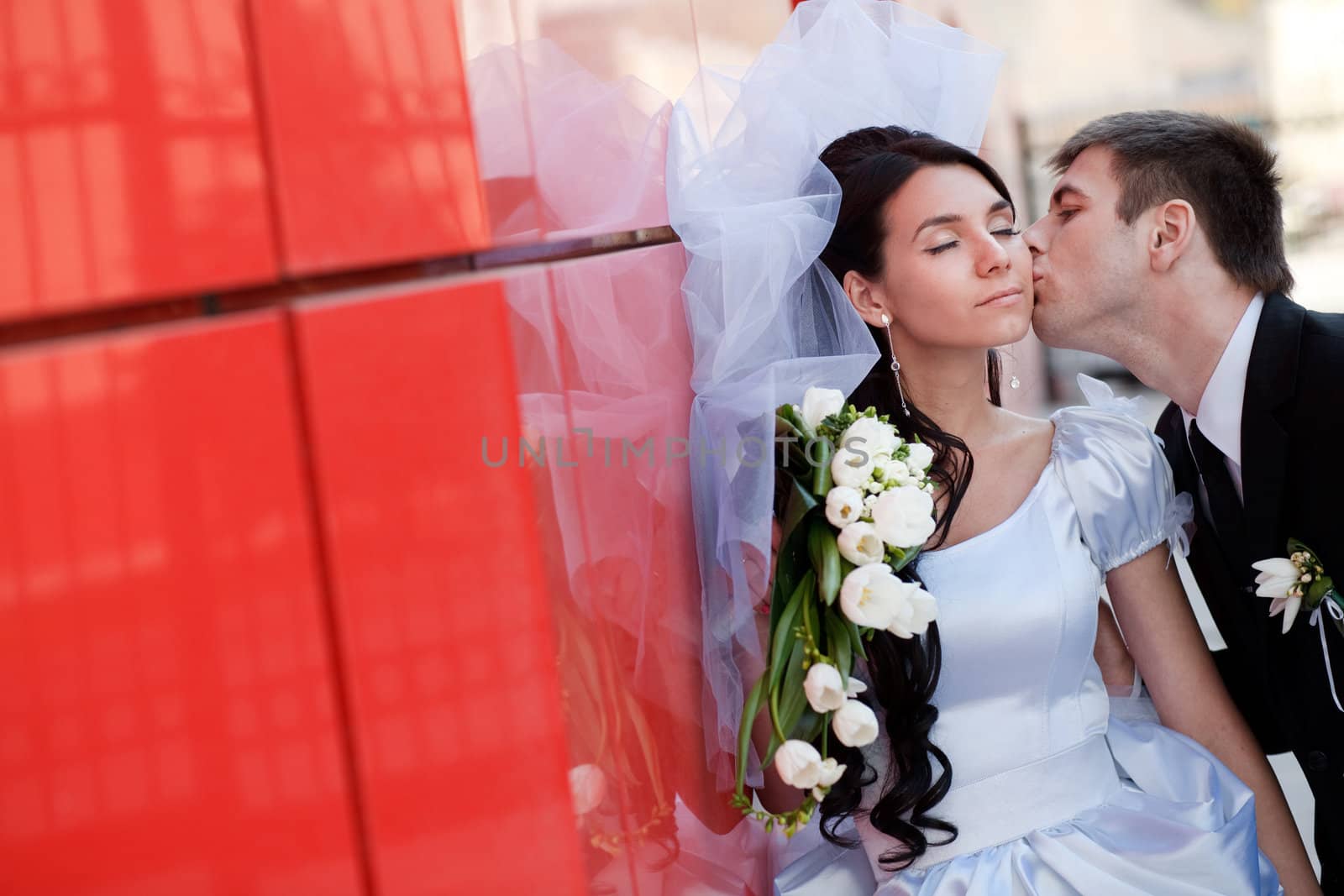 kiss of the couple by the red wall