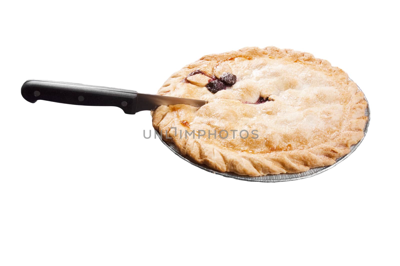 Cherry pie in a dish with a knife preparing to cut a slice out of it, isolated on white