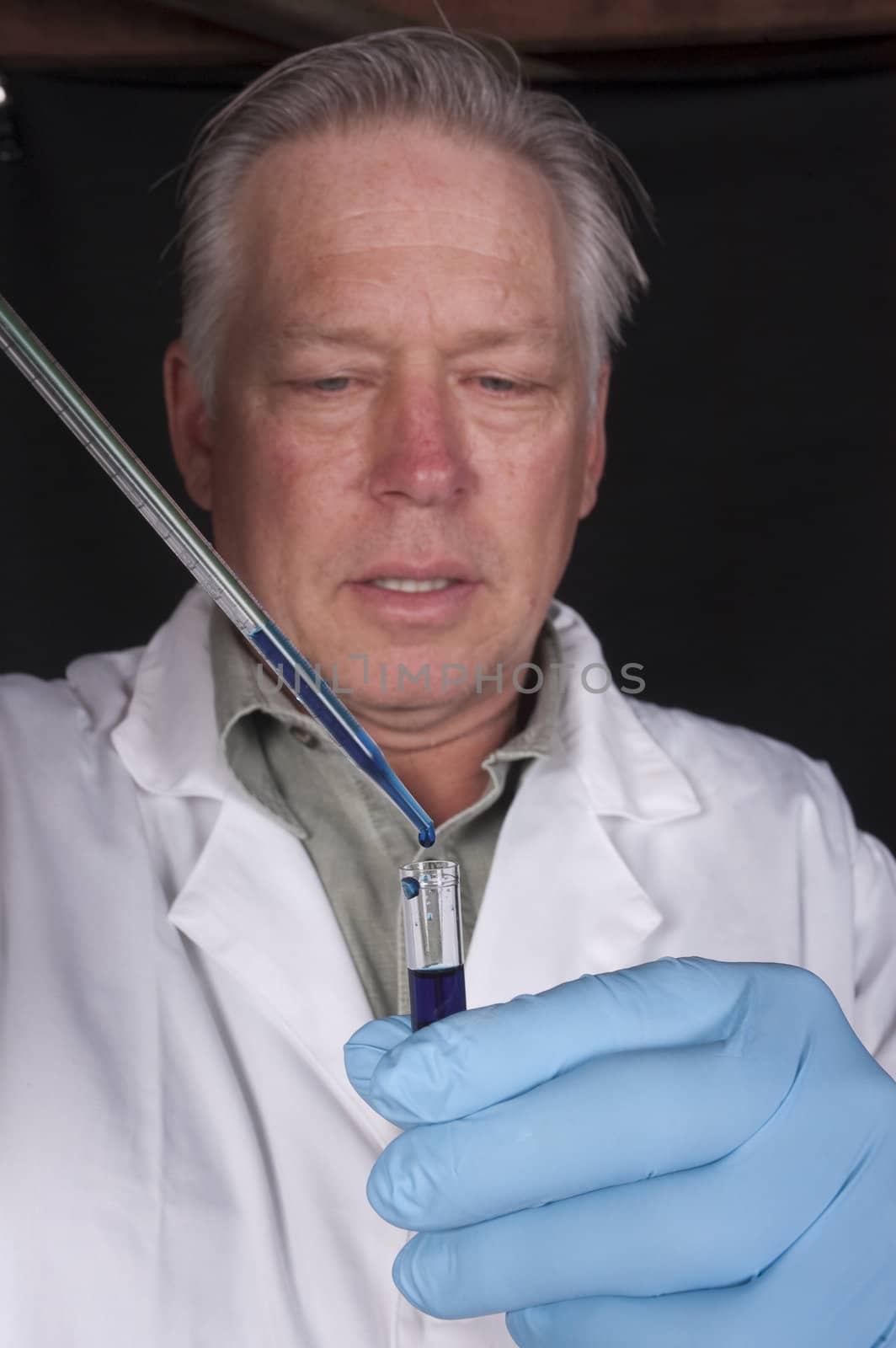 chemical engineer, doctor or research scientist using a pipette to take a sample of a chemical from a test tube