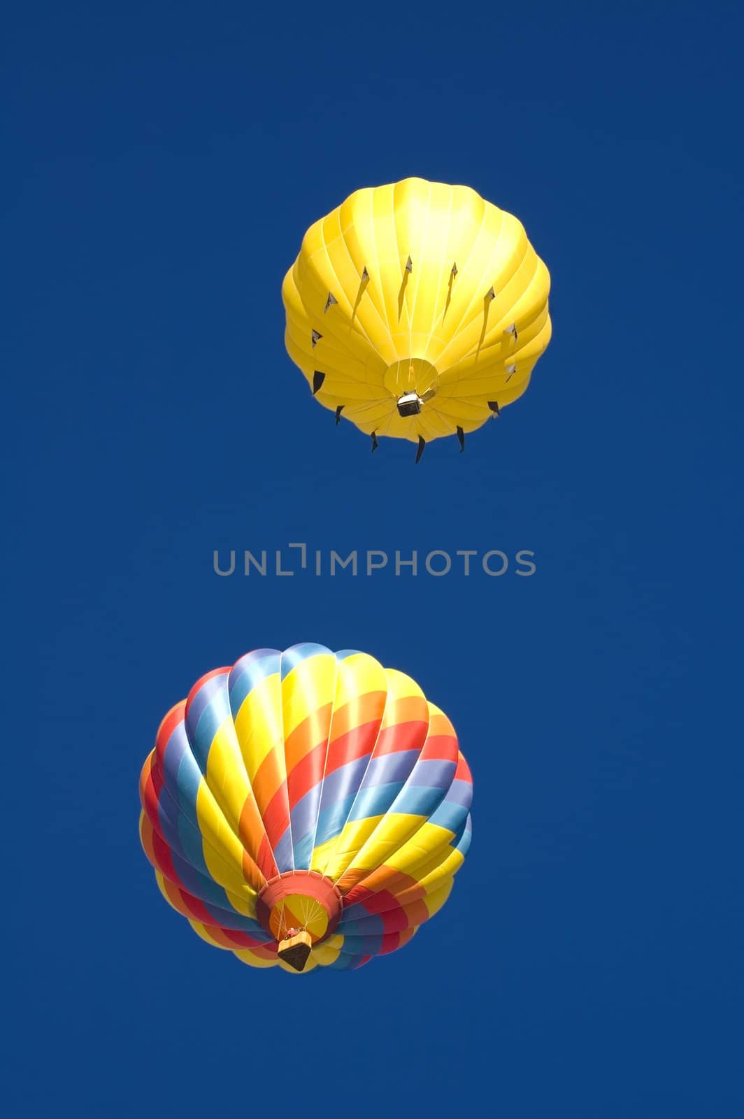 two of the balloons at the Taos balloon festival sailing off into a deep blue sky