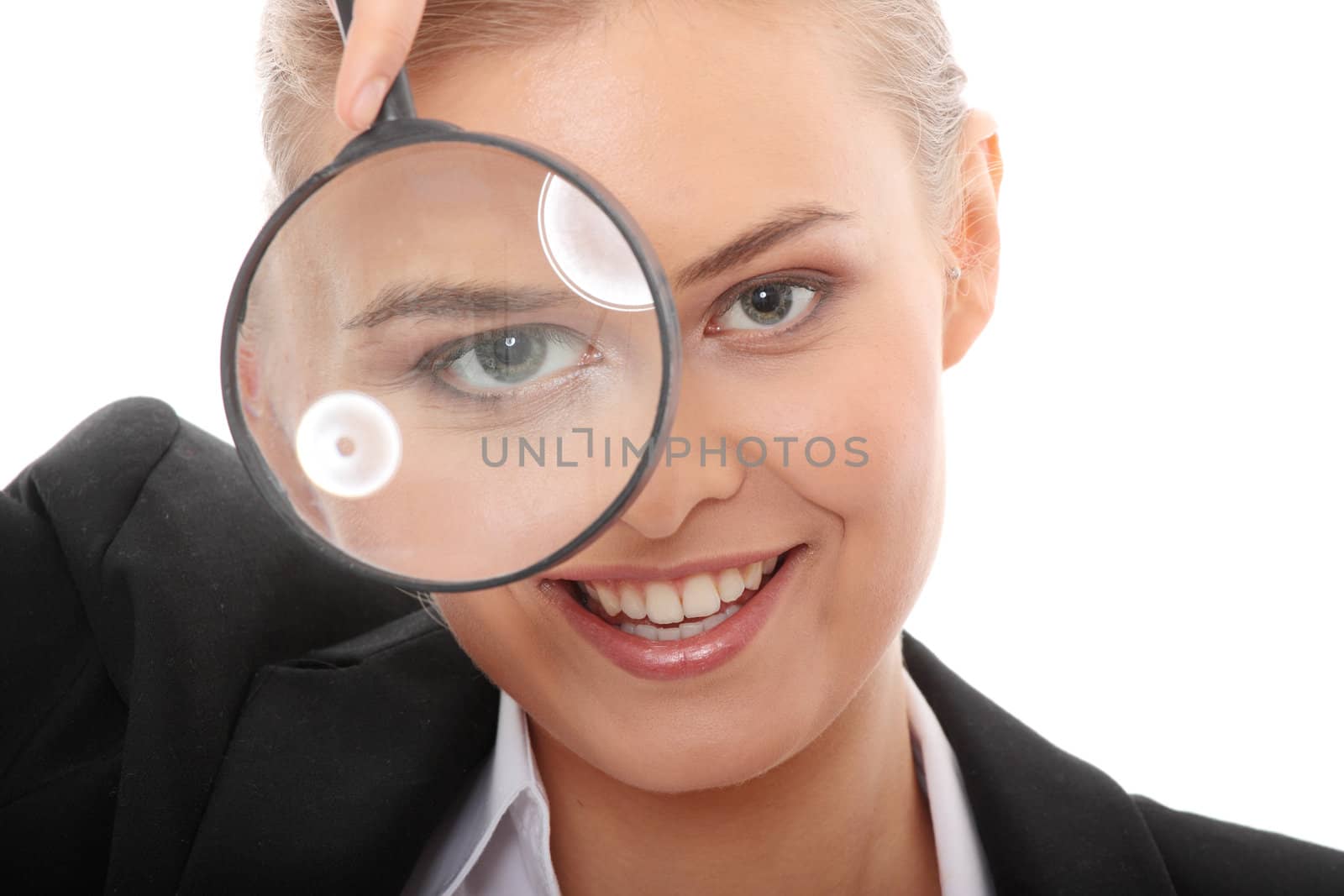 Young attractive smiling business woman looking into a magnifying glass, isolated on white background