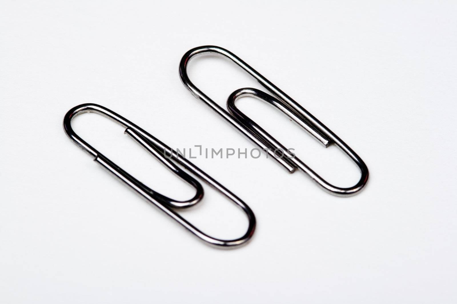 Muchos clips de metal sobre fondo blanco - A lot of metal paperclips on a white background