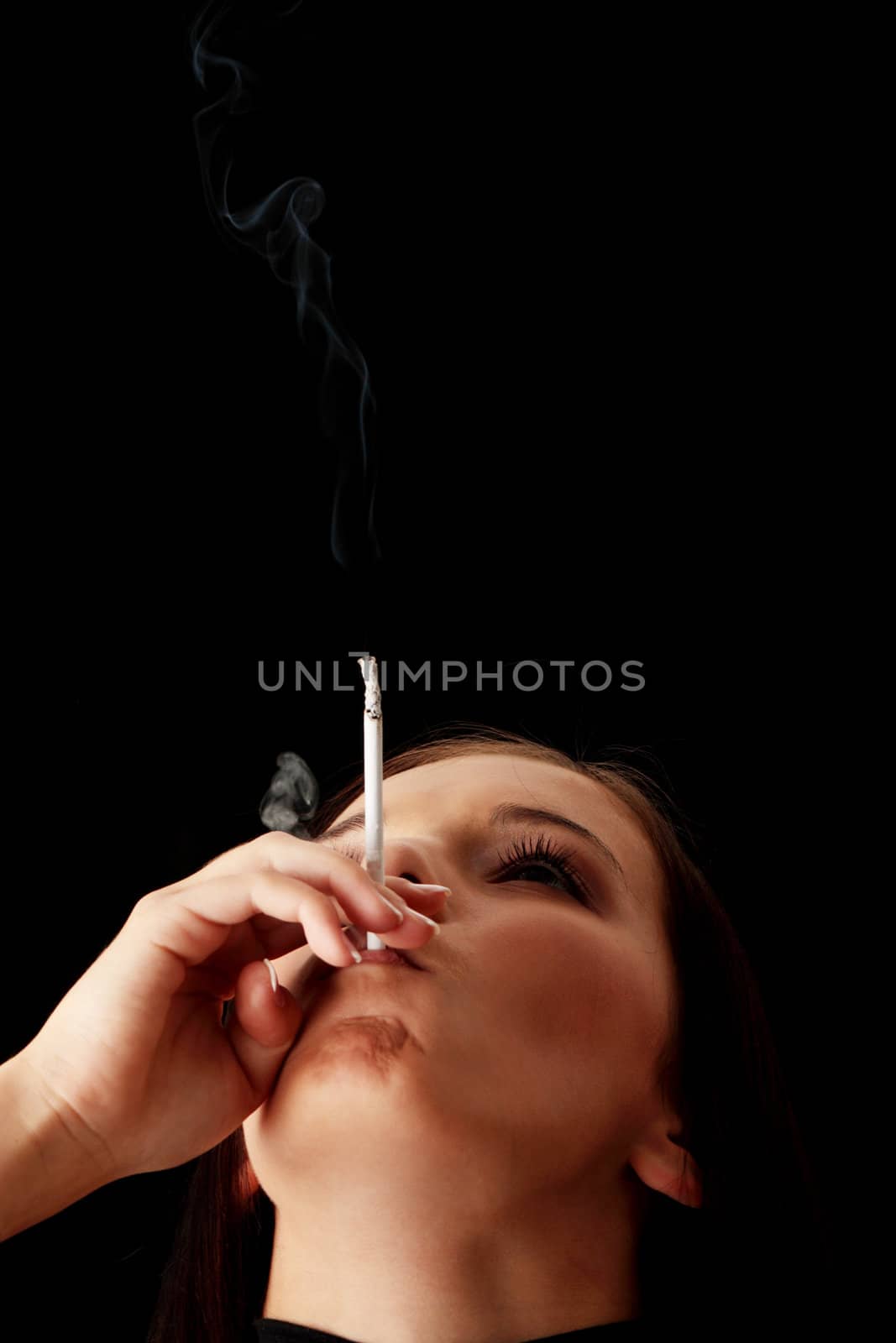 Young woman smoking over black background