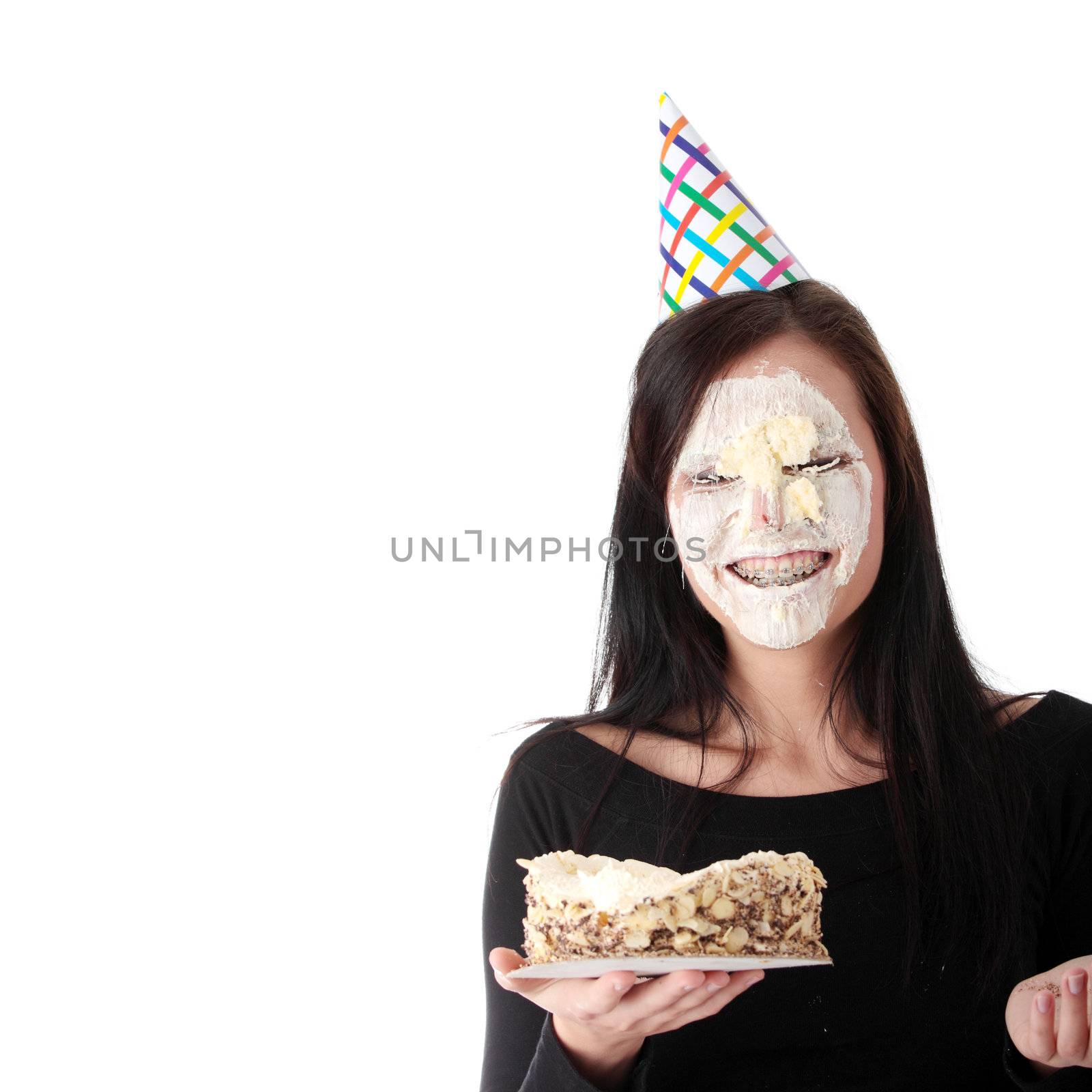 Funny portrait of beautiful young caucasian woman with birthday cake on her face, isolated on white background