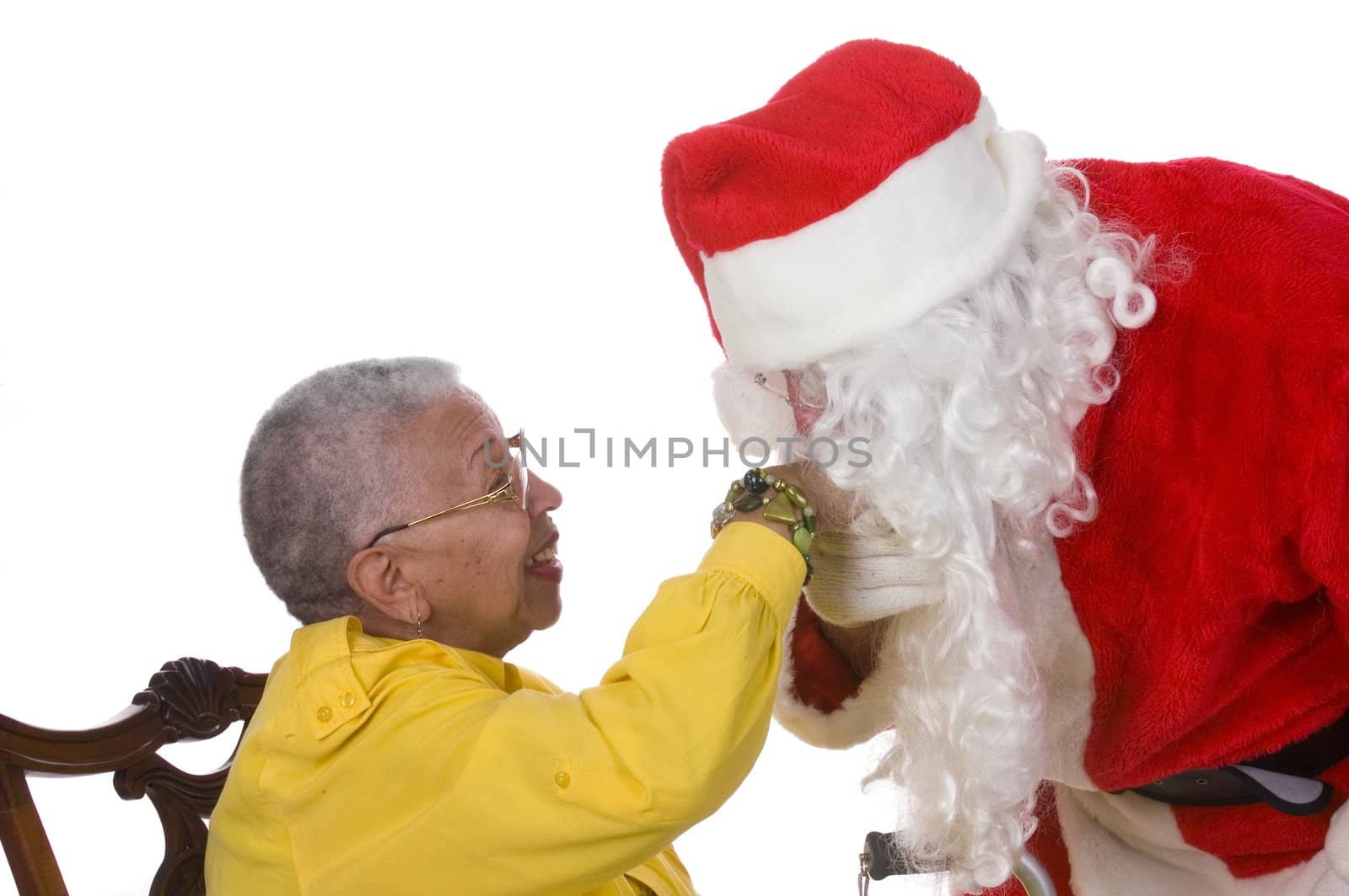 Pleasant middle-aged bearded man in a santa suit kissing the hand of an elderly African American lady - isolated on a white background